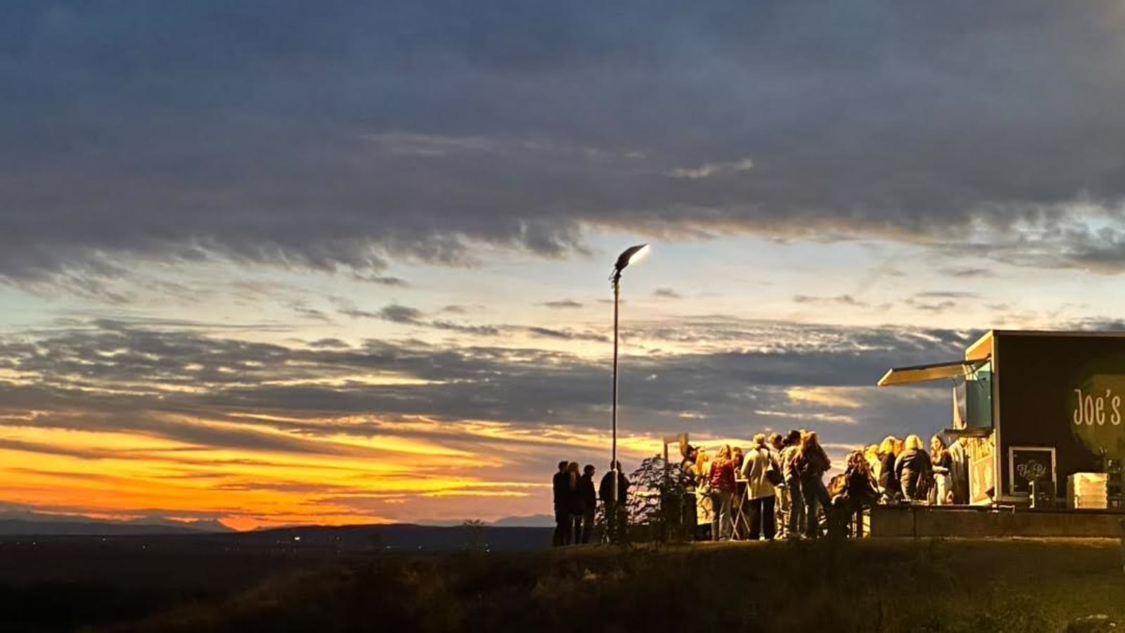 Sonnenuntergang über dem Neusiedler See, die Gäste als Silhouetten auf der Mauer