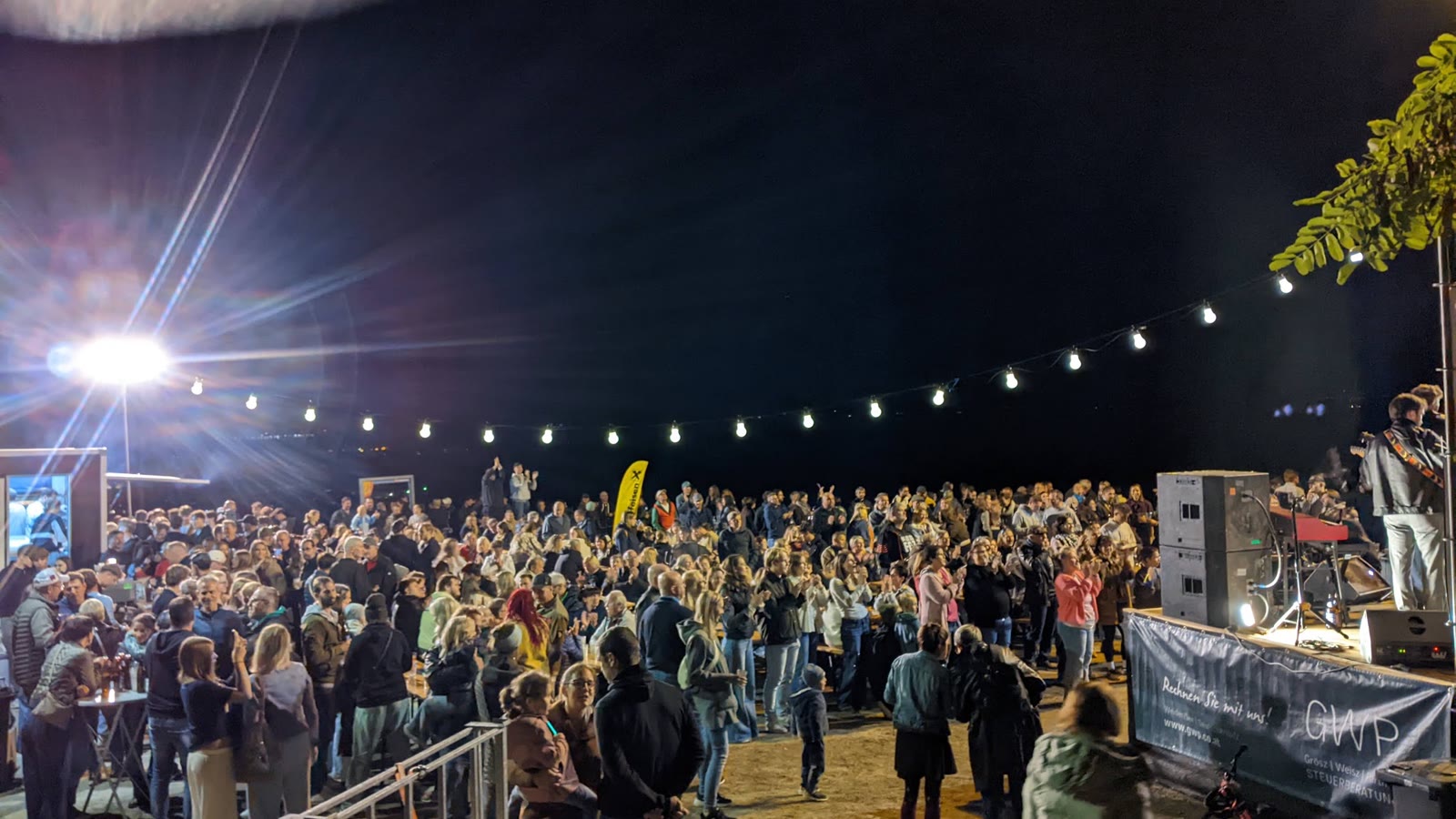 Lichterkette über dem Platz, davor die Menschen in der Nacht